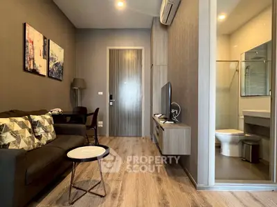 Modern living room with stylish decor and open view to bathroom, featuring sleek furniture and wooden flooring.