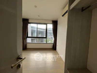 Spacious and well-lit bedroom with large windows offering ample natural light, complemented by elegant drapery and a built-in wardrobe.