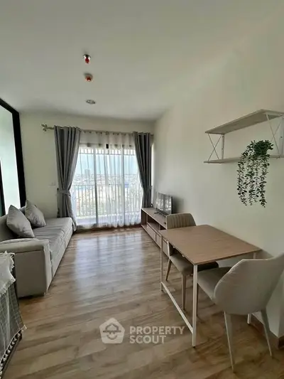 Modern living room with wooden flooring, cozy sofa, and large window offering city views.