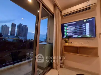 Modern living room with city view and balcony access, featuring a wall-mounted TV and air conditioning.