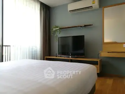 Modern bedroom with TV and air conditioning, featuring sleek furniture and natural light.