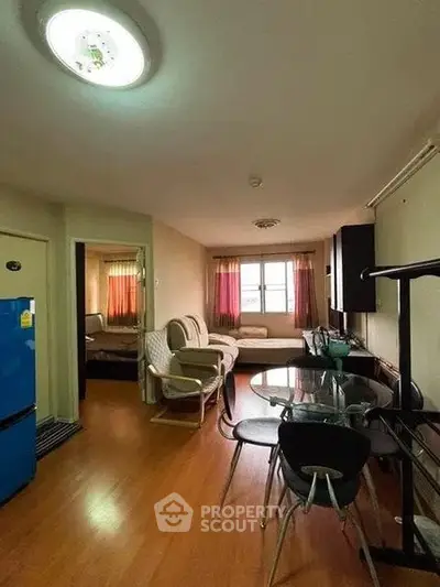 Cozy living room with dining area and bedroom view, featuring wooden flooring and natural light.