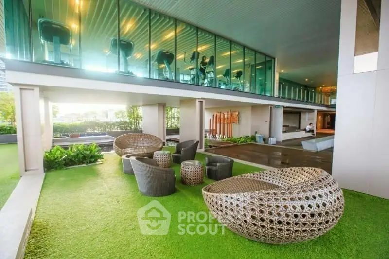 Luxurious outdoor seating area with modern gym view and lush greenery.