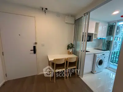 Modern apartment interior with compact kitchen and dining area featuring washing machine and sleek design.