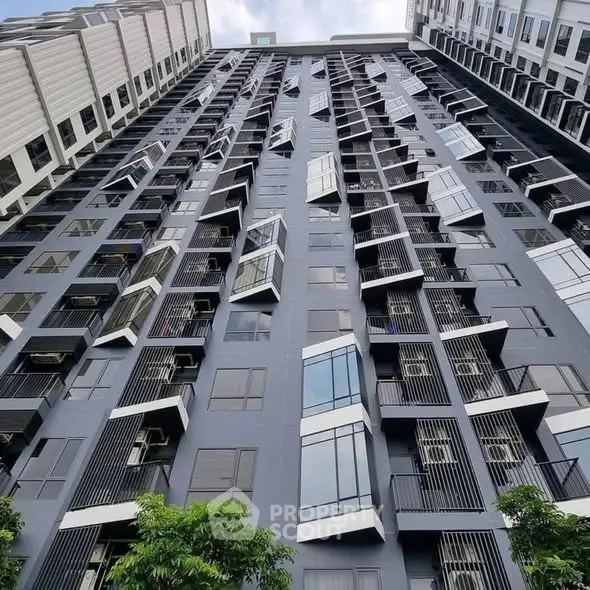 Modern high-rise building with unique geometric window design and sleek facade.