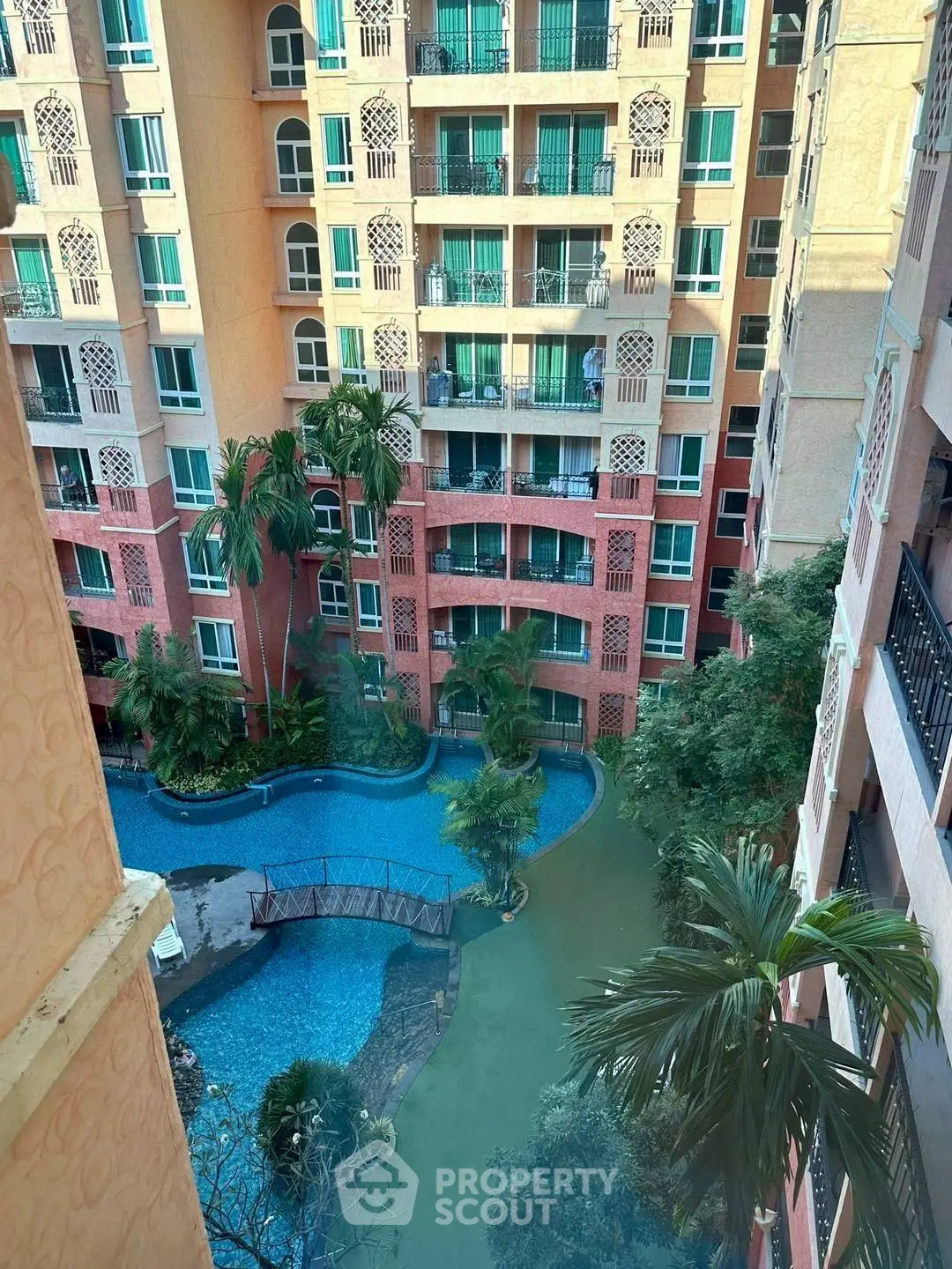 Stunning view of a residential building with a pool and lush greenery.