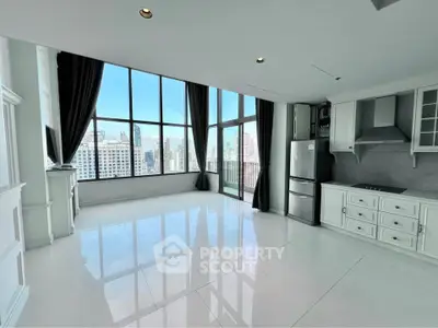Spacious modern living room with panoramic city views and sleek kitchen area.