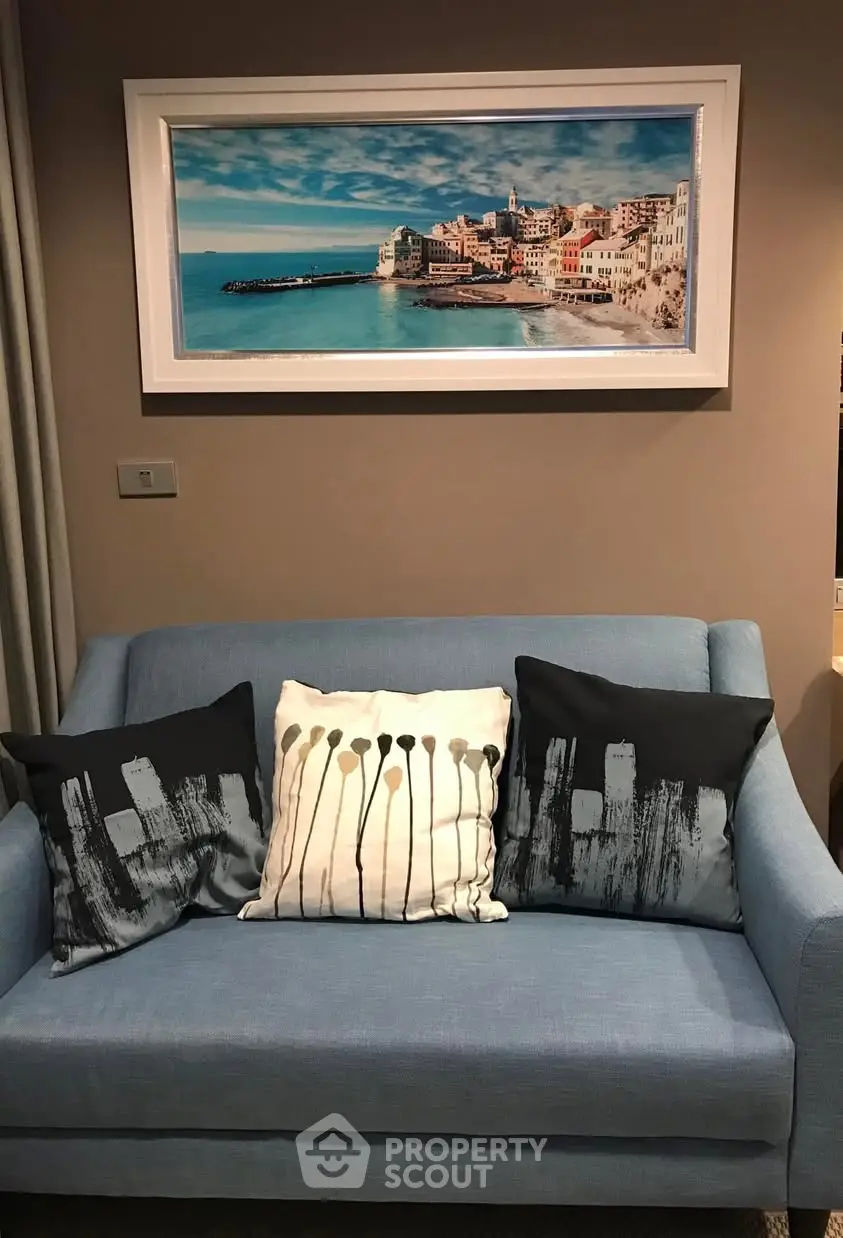 Stylish living room with blue sofa and artistic cushions under a scenic framed picture.