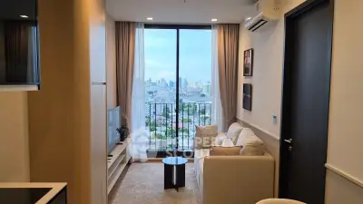 Modern living room with city view, cozy sofa, and large window balcony access.
