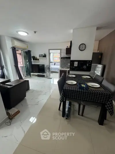 Modern open-plan living room and kitchen with sleek furnishings and natural light.