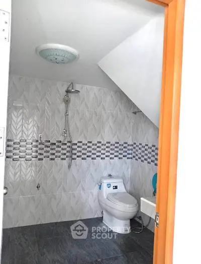 Modern bathroom with sleek design and efficient use of space under the stairs.