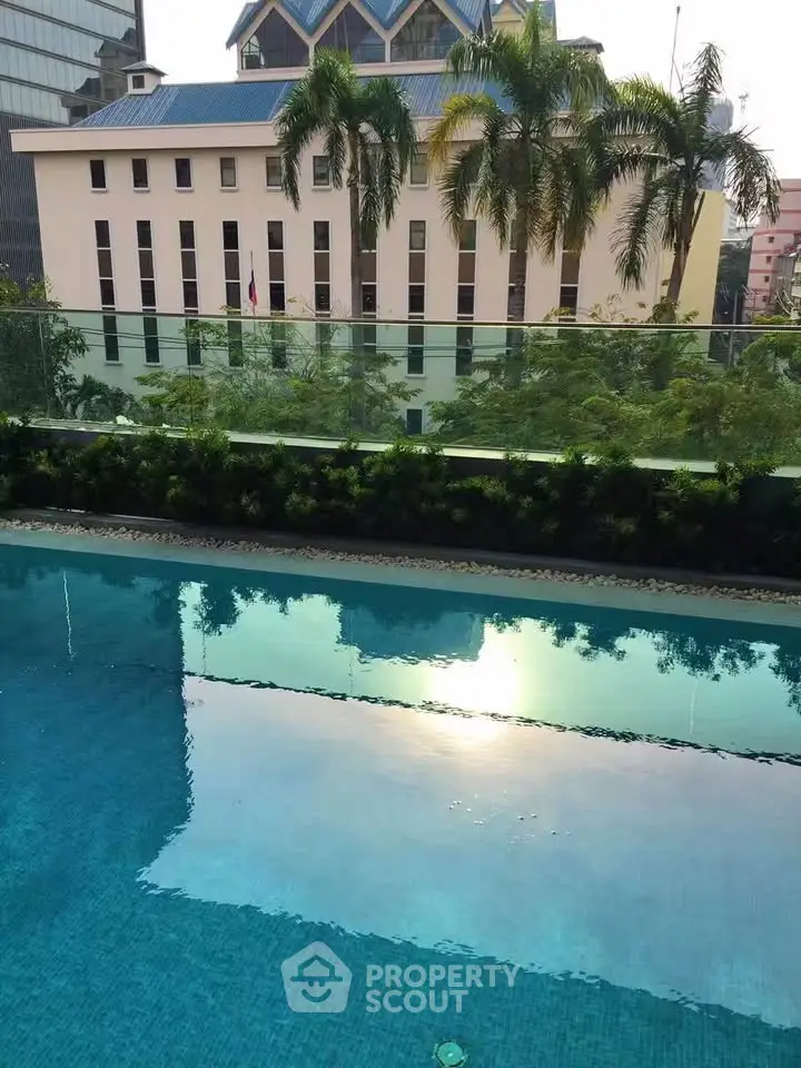 Luxurious poolside view with cityscape backdrop and lush greenery, perfect for urban relaxation.