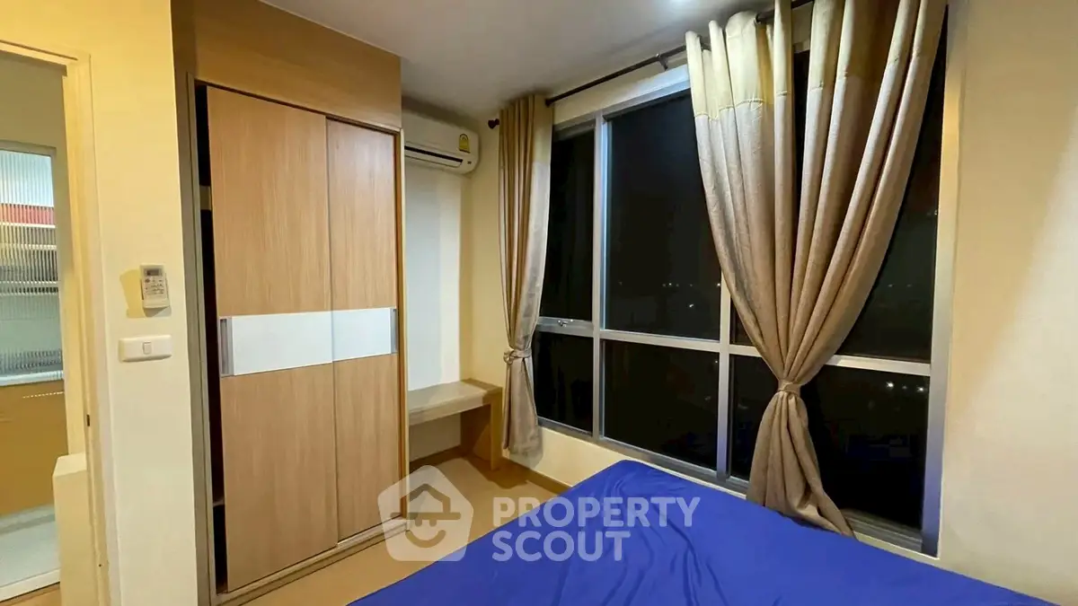 Cozy bedroom with large window and modern wardrobe, ideal for urban living.