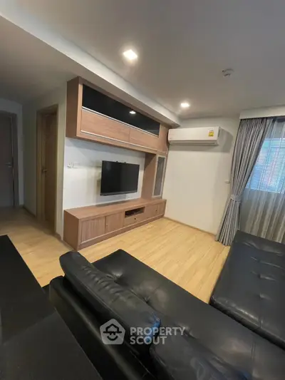 Modern living room with sleek black leather sofa and wall-mounted TV unit