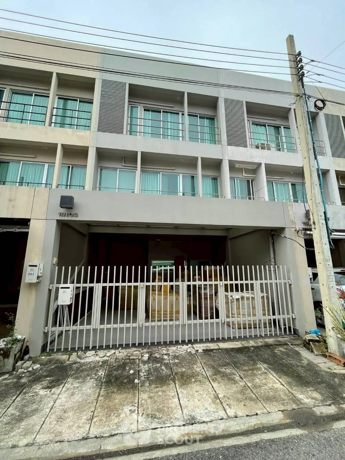 Modern multi-story building with gated entrance and large windows, ideal for urban living.