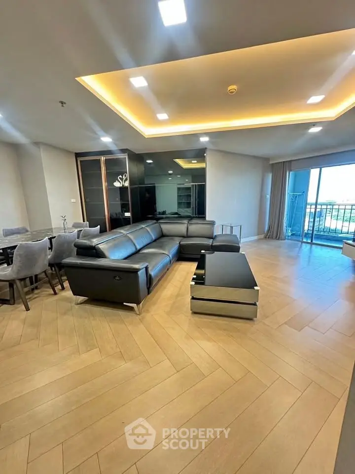 Spacious modern living room with elegant leather sofa and large balcony view.