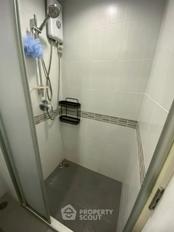 Compact bathroom shower area with modern fixtures and tiled walls