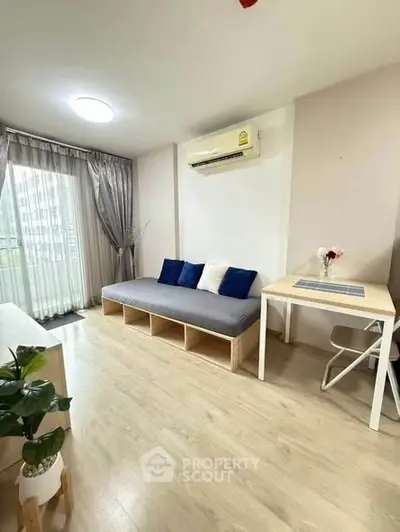 Modern living room with sleek design, featuring a cozy sofa, air conditioning, and natural light from large windows.