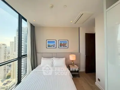 Modern bedroom with city view in high-rise apartment, featuring stylish decor and natural light.