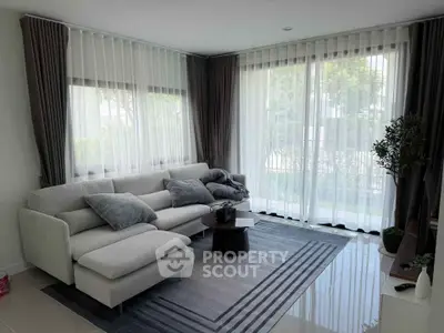 Elegant living room with large windows and modern decor, featuring a cozy sofa and stylish rug.