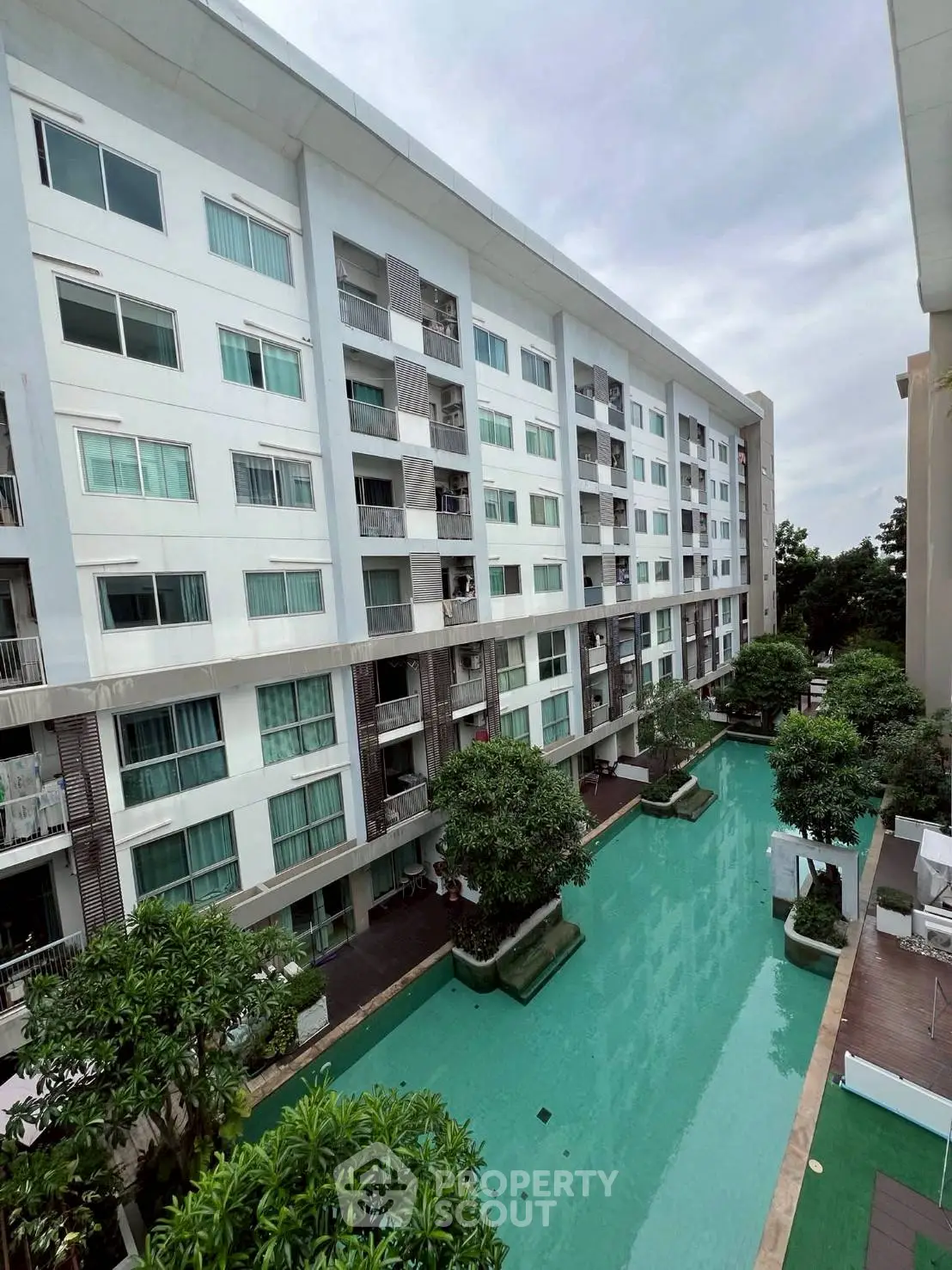 Modern apartment building with pool view and lush greenery