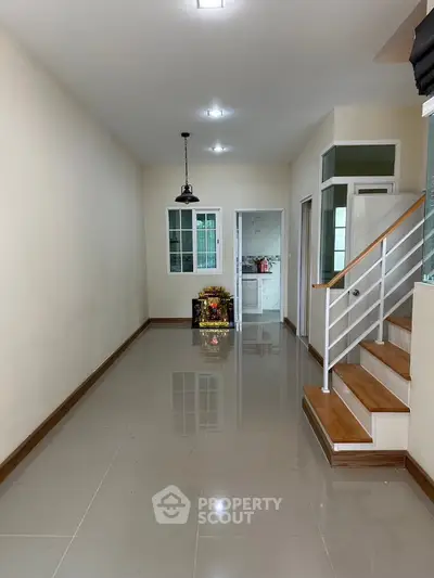 Spacious hallway with modern staircase and glossy tiled flooring