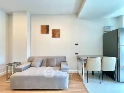 Modern living room with cozy gray sofa and dining area in open layout apartment.