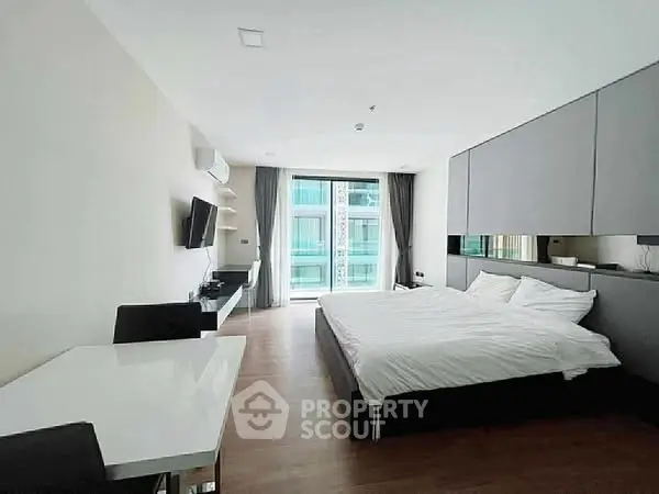 Modern bedroom with large windows and sleek furnishings in a stylish apartment.