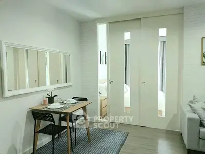 Modern apartment interior with dining area and sliding doors leading to bedroom.