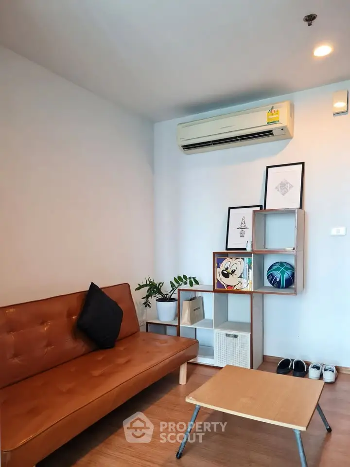 Modern living room with stylish decor and air conditioning, featuring a cozy sofa and wall art.