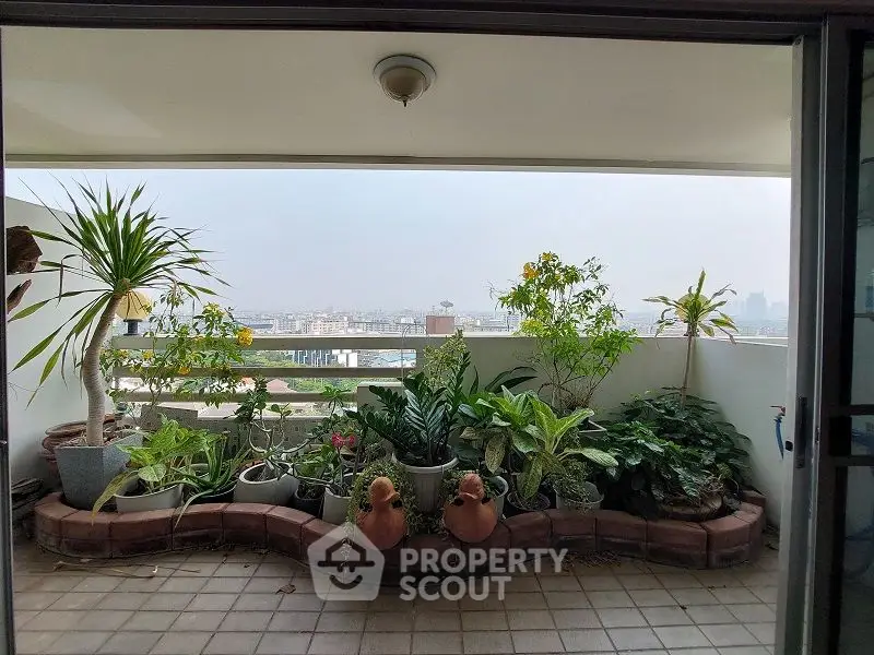 Spacious balcony with lush greenery and city view, perfect for relaxation.
