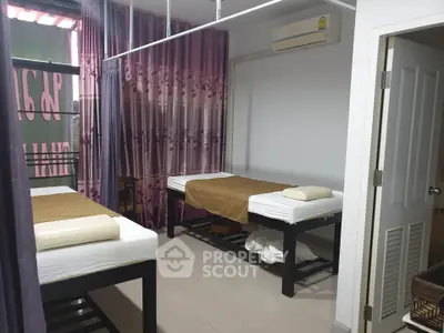 Spacious massage room with two beds and air conditioning, ideal for relaxation and wellness services.