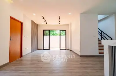 Spacious modern living room with large windows and wooden flooring.