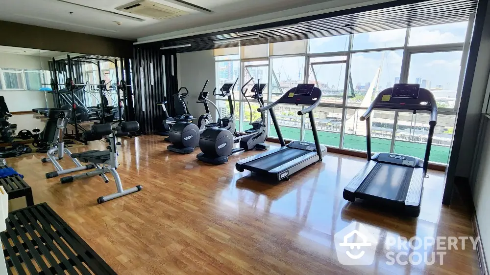 Spacious gym with modern equipment and city view in luxury apartment complex