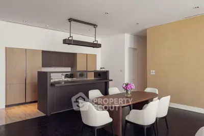 Modern kitchen with open layout and elegant dining area featuring sleek cabinetry and stylish lighting.