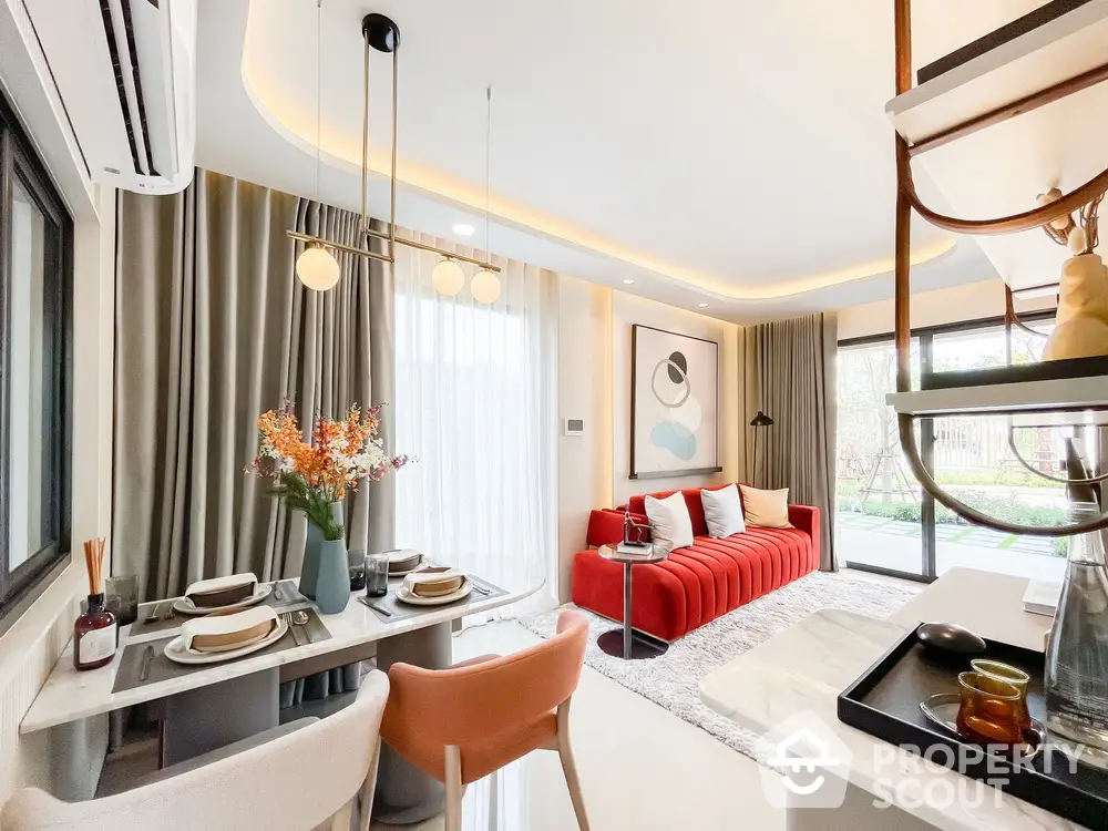 Modern living room with stylish decor and natural light, featuring a red sofa and elegant dining area.