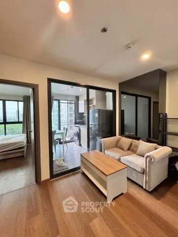 Modern apartment interior with open living room and kitchen, featuring large windows and stylish furniture.