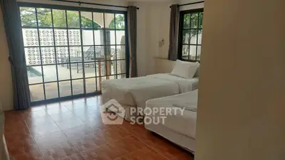 Spacious bedroom with twin beds and large windows overlooking a patio.