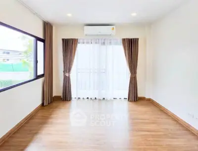 Spacious empty room with wooden flooring and large window, perfect for customization.