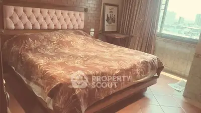 Cozy bedroom with large bed and city view window, perfect for relaxation.