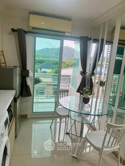 Charming kitchen with glass dining table and scenic balcony view in modern apartment.