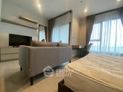Modern studio apartment with stylish furniture and large windows offering natural light.