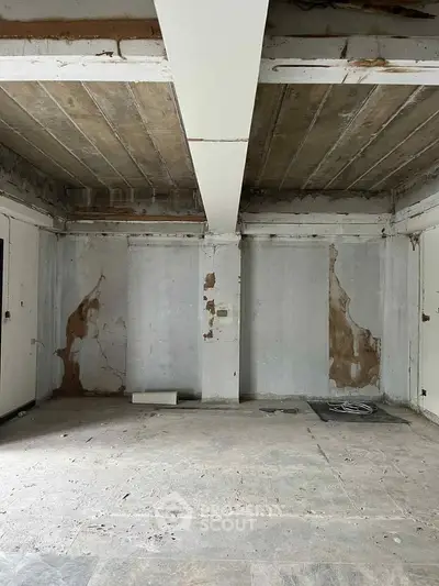 Spacious unfinished room with exposed concrete ceiling and walls, ideal for renovation.