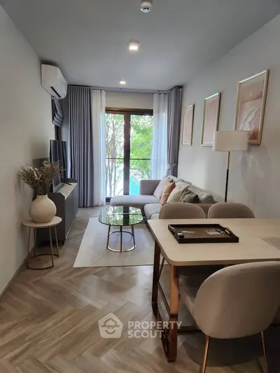 Modern living room with stylish decor, cozy seating, and natural light from large window.