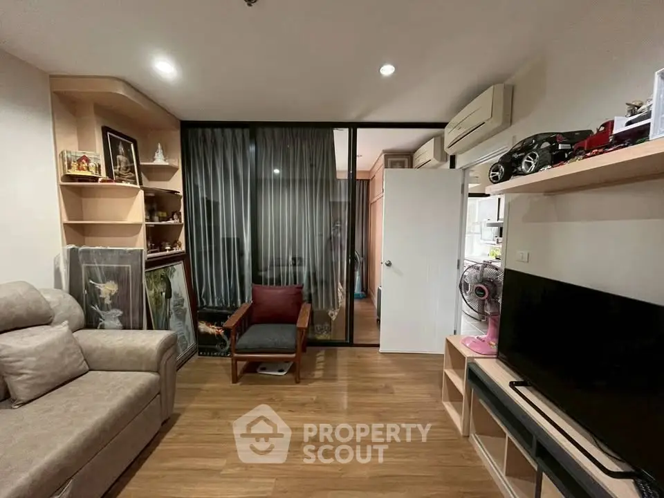 Cozy living room with modern decor and wooden flooring, featuring a comfortable sofa and entertainment setup.