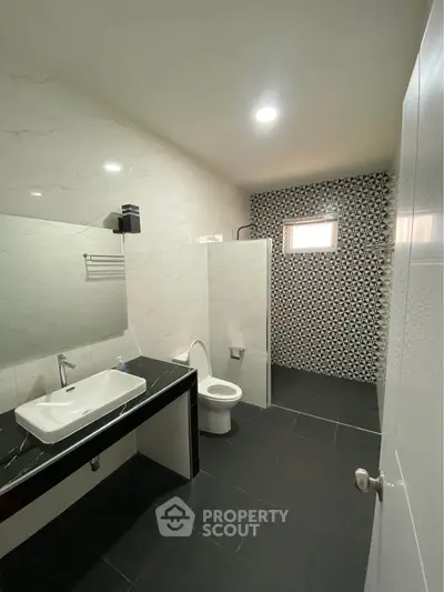 Modern bathroom with sleek black and white design, featuring a spacious layout and stylish fixtures.
