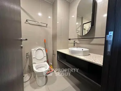 Modern bathroom with sleek fixtures and elegant design, featuring a round mirror and stylish countertop.
