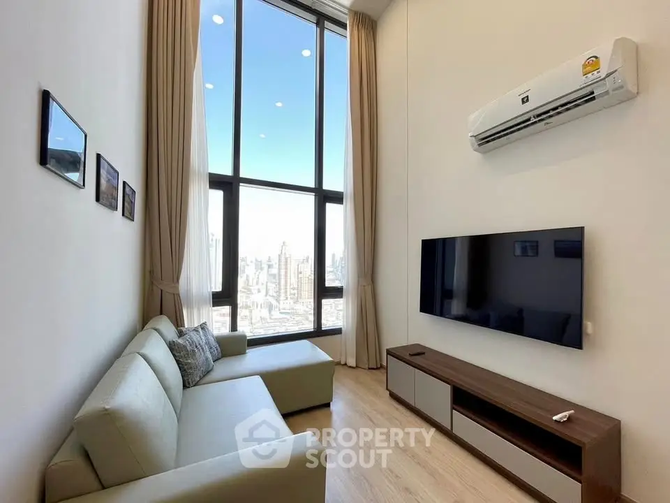 Modern living room with high ceilings and city view, featuring a sleek sofa and wall-mounted TV.