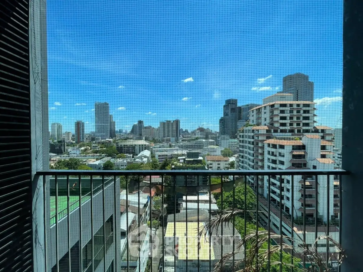 Stunning cityscape view from a high-rise balcony, showcasing urban skyline and clear blue skies.
