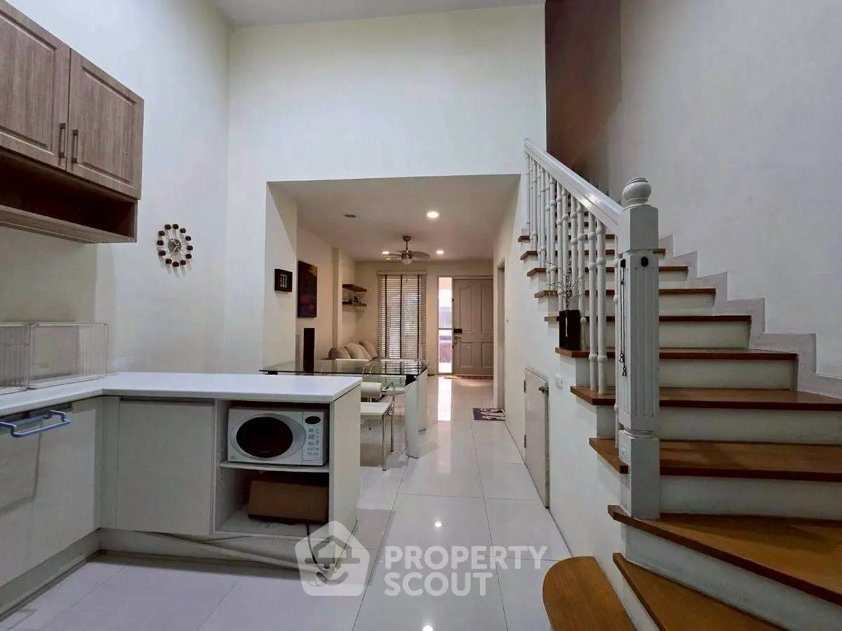 Modern open-plan living room with staircase and kitchen area